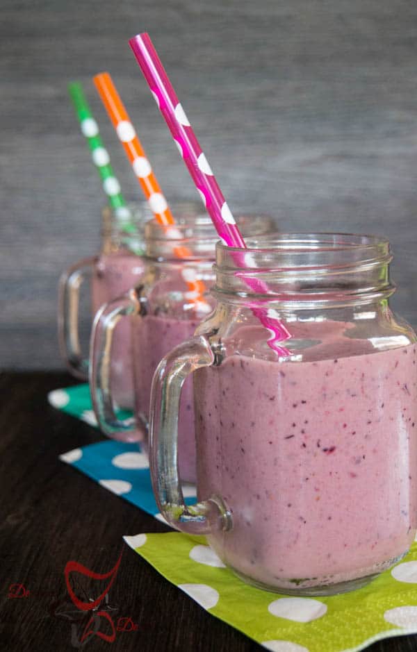 Image of a fruit smoothie in a clear mason jar mug with polka dot straws