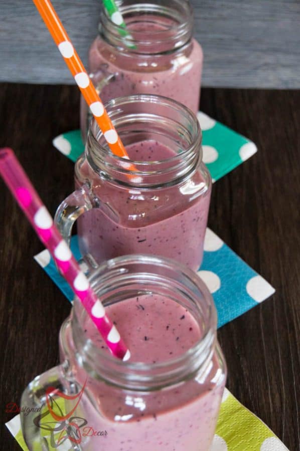 picture of 3 fruit smoothies in a clear mason jar mug with polka dot napkins and straws