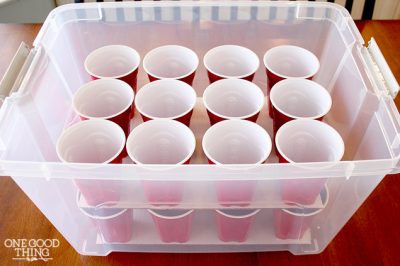 Clear plastic bin with red solo cups to hold Christmas ornaments