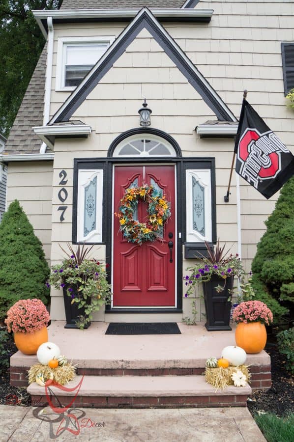 Front entryway decorated with fall pumpkins, mums, and mini hay bales.