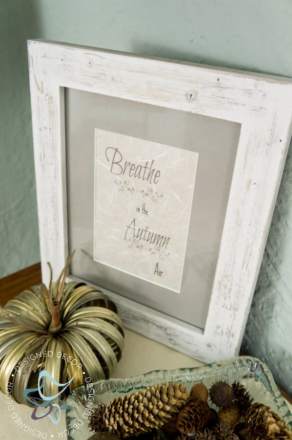 fall-vignette with a bowl of pine cones, a metal pumpkin, and fall quote in a picture frame