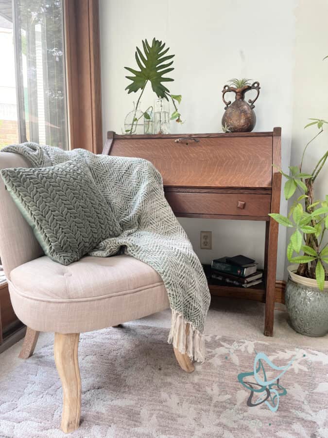 a chair draped with a pillow and blanket sitting in front of a desk