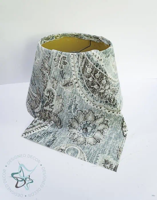 once fabric is dry, trim extra fabric around edges of lampshade