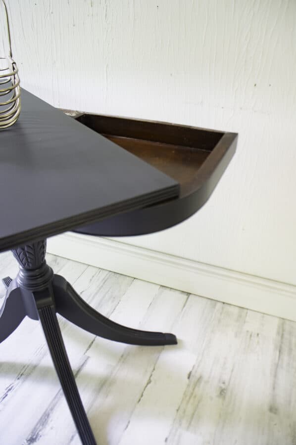 close up image of a half moon table with the top open to reveal the hidden compartment