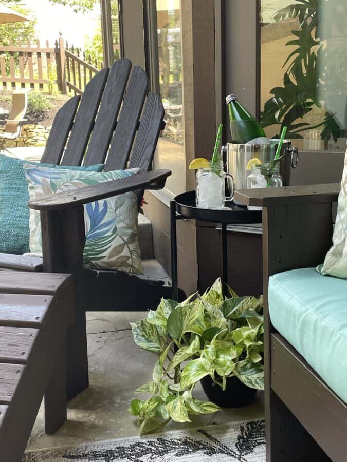 image of an Adirondack with decorative outdoor pillows and a side table with drinks