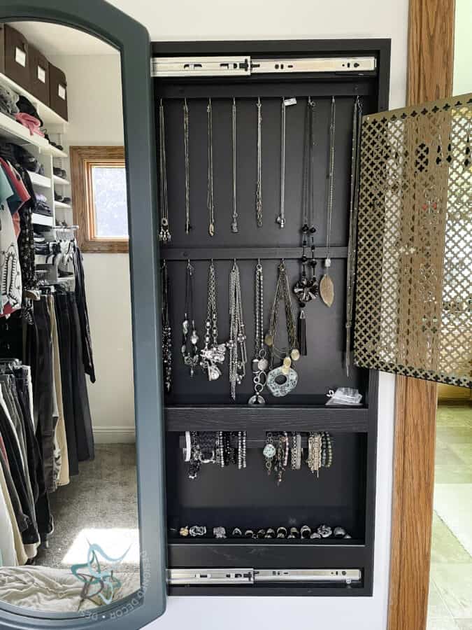 sliding mirror jewelry cabinet with mirror open and showing the hanging necklace area