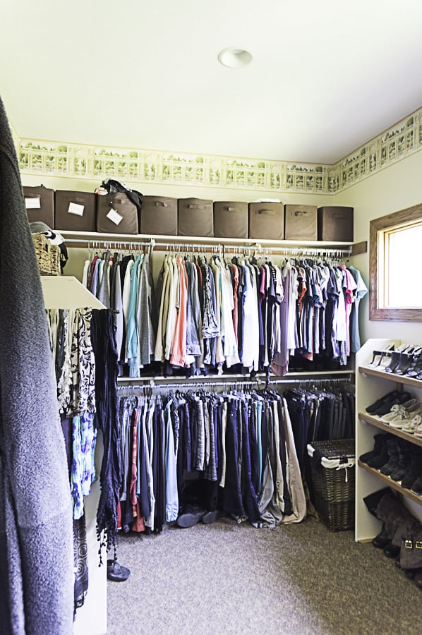 a walk-in closet with fabric storage cubes and hanging clothes