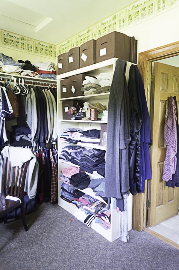 a messy walk-in closet with open shelving