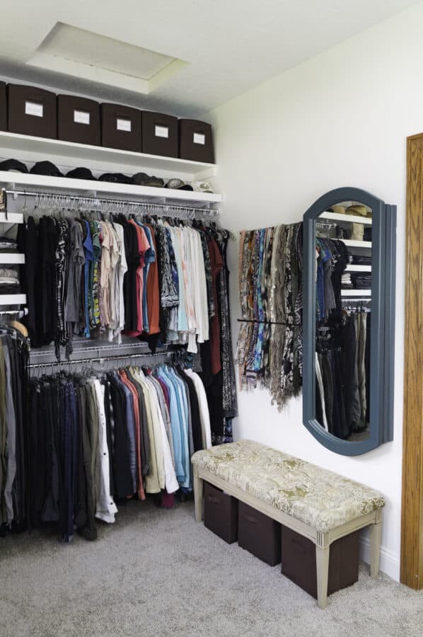 image of a mirror hanging on a closet wall with a tufted bench below the mirror jewelry cabinet