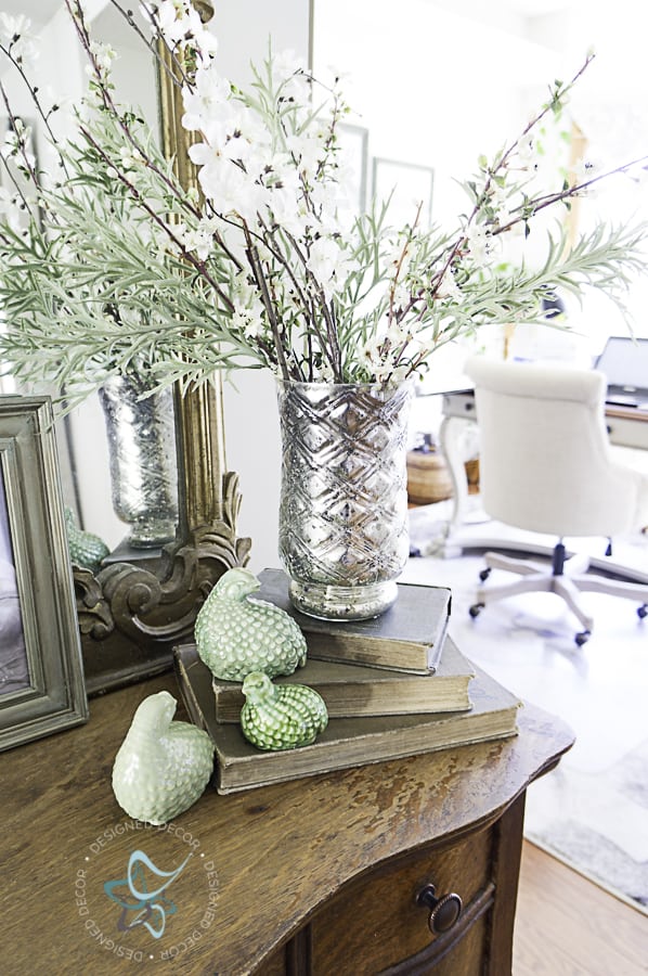 Spring entryway with stacked books and a vase of spring florals