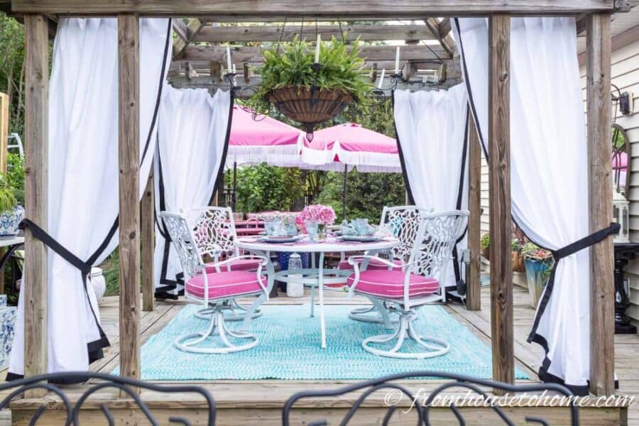 outdoor round dining table with wood trellis above 