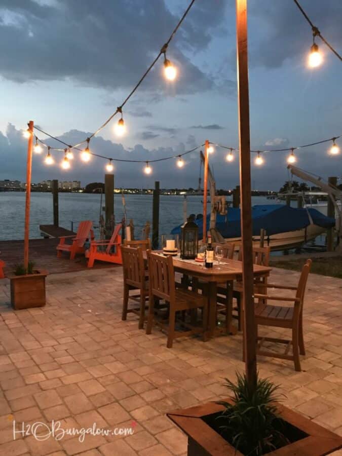 string lights hanging on poles above an outdoor dining table