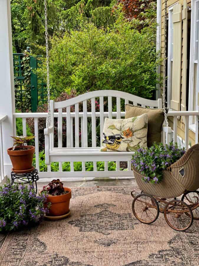 white porch swing with potted plants placed around