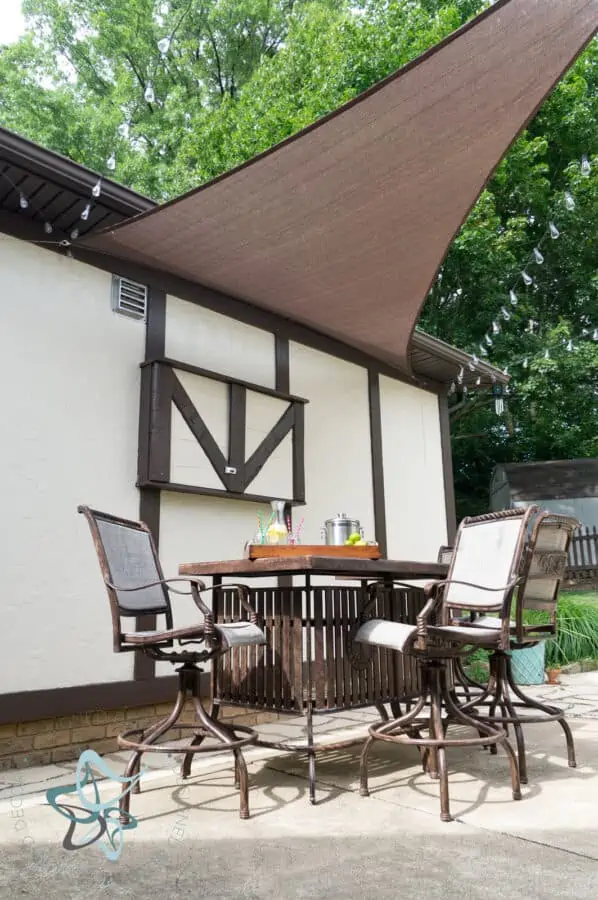 patio with a metal bar table and chairs with outdoor TV cabinet closed in the background