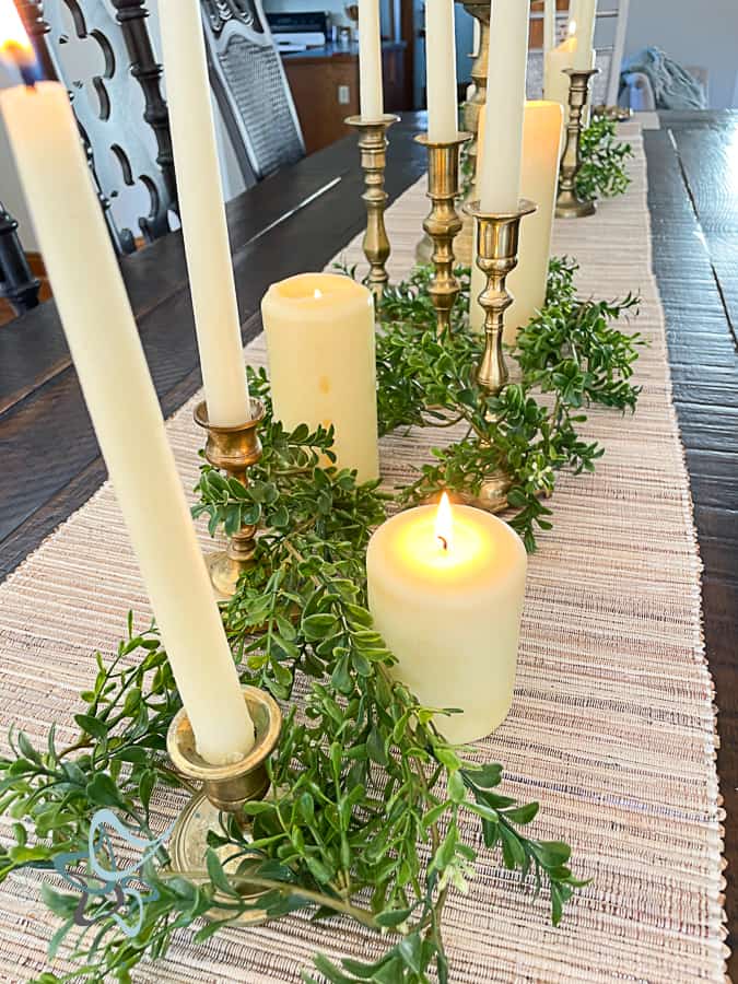 Dining tablescape with candles, candlesticks, and greenery