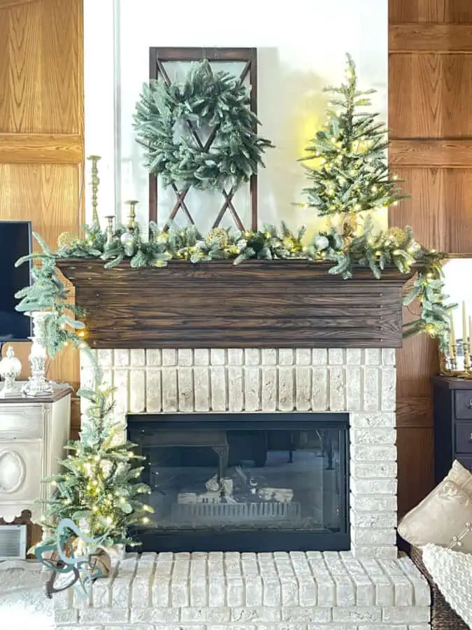 Fireplace mantle decorated for Christmas using lighted garland and a wreath